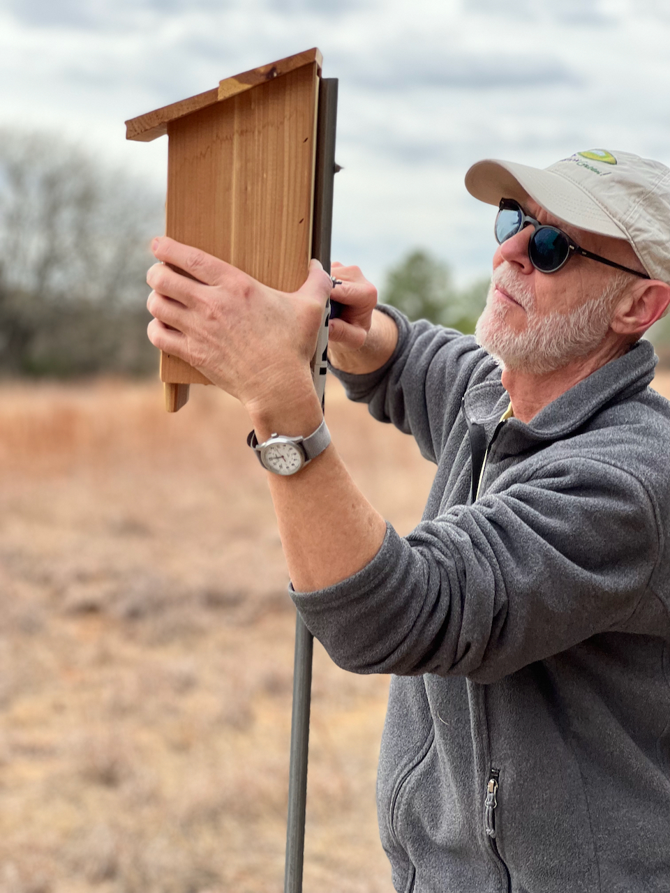 Photo of a man installing a bluebird box on a post.